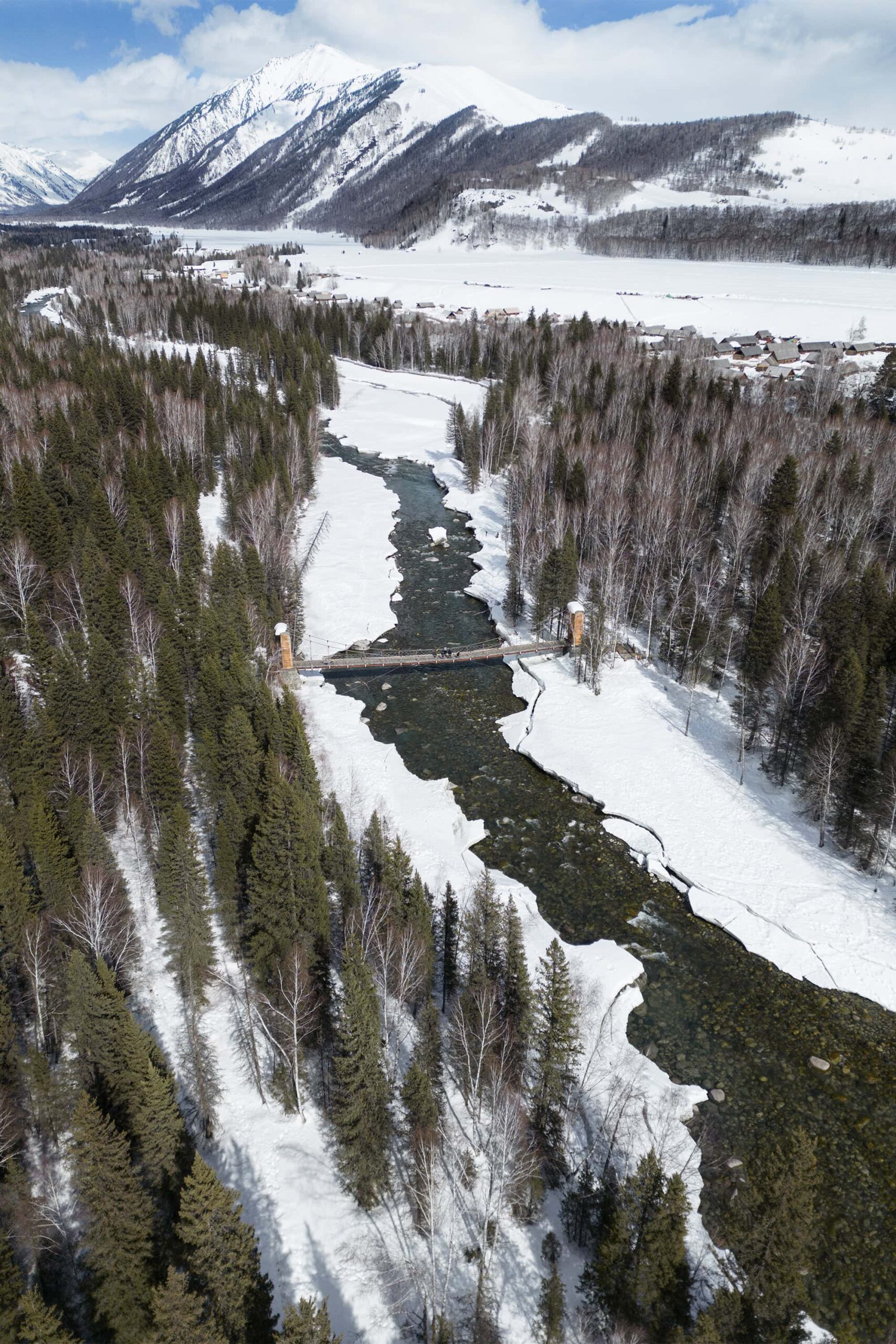 Vertical Xinjiang travel guide highlight: Hemu Village’s spring thaw, with rivers snaking through snow-fringed valleys