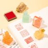 Five Blessings Palace Cat Ink Stamps from Beijing Palace Museum with their impressions displayed on an open book