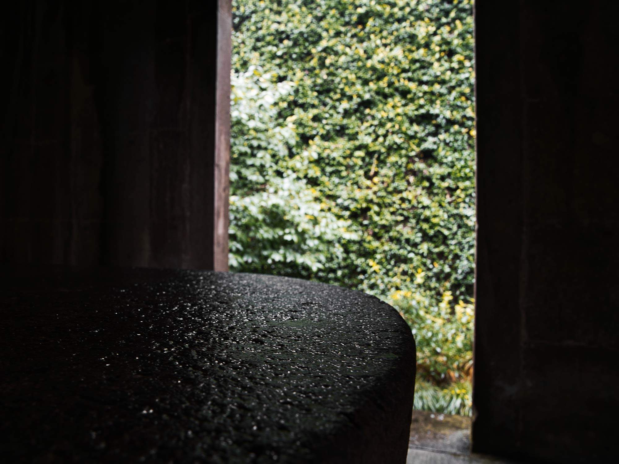 View through a wooden doorway of a small pavilion, framing a lush green scene outside