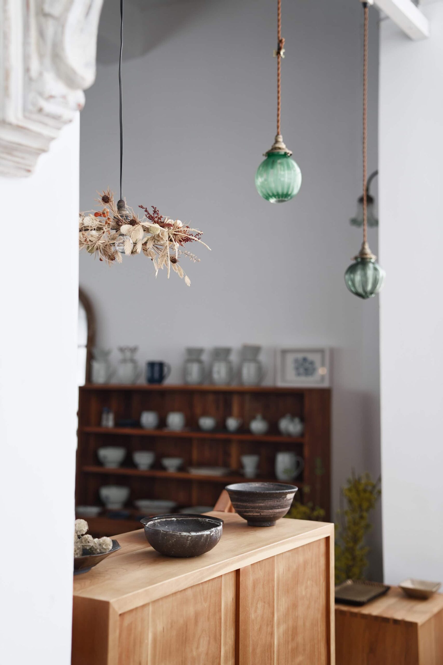 Cozy corner of Soukai featuring handcrafted Japanese ceramic bowls, decorative elements and hanging wind chimes in natural light