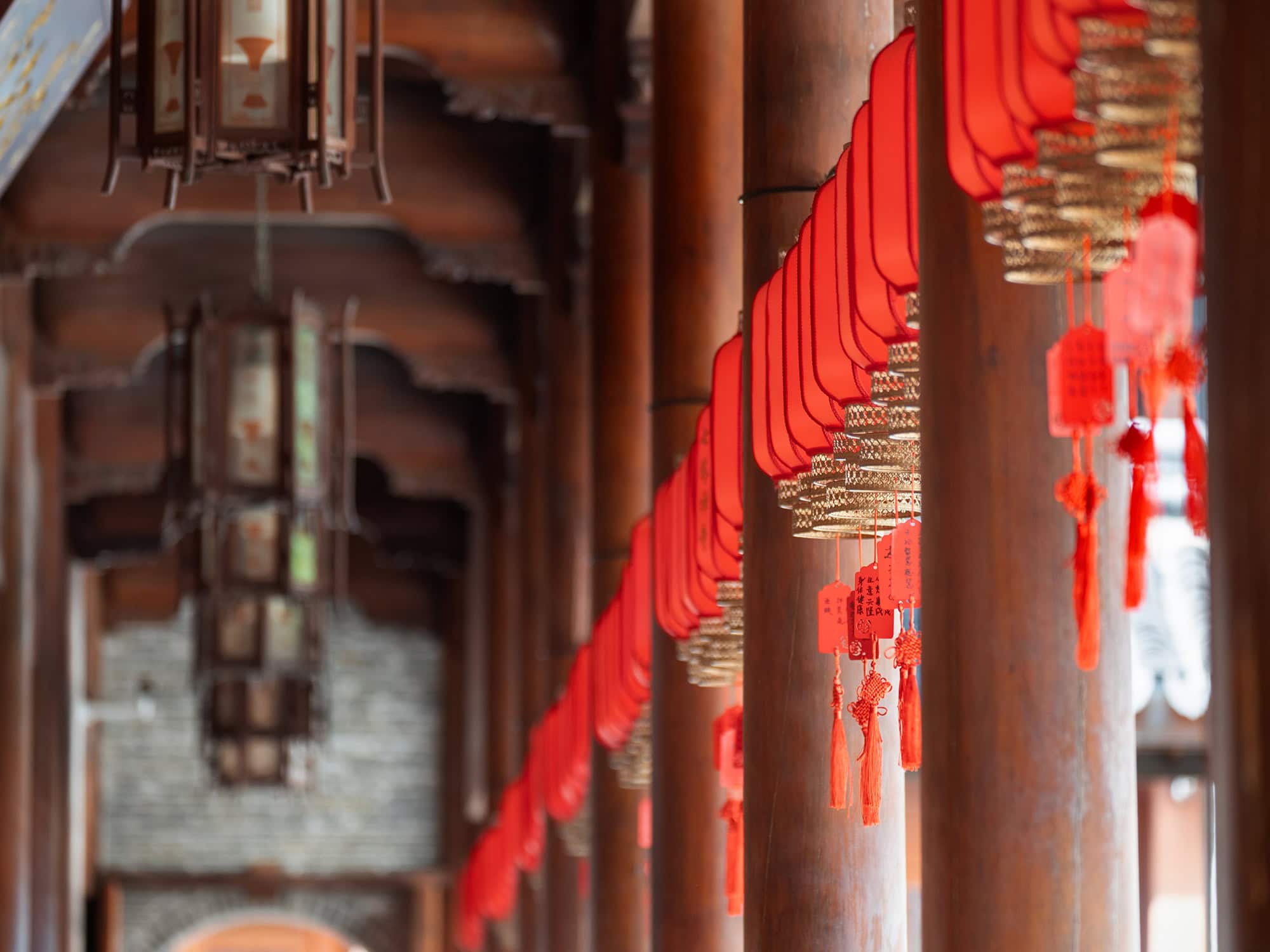 Ornate ceiling lighting fixtures and traditional red lanterns suspended throughout the interior of Qita Temple