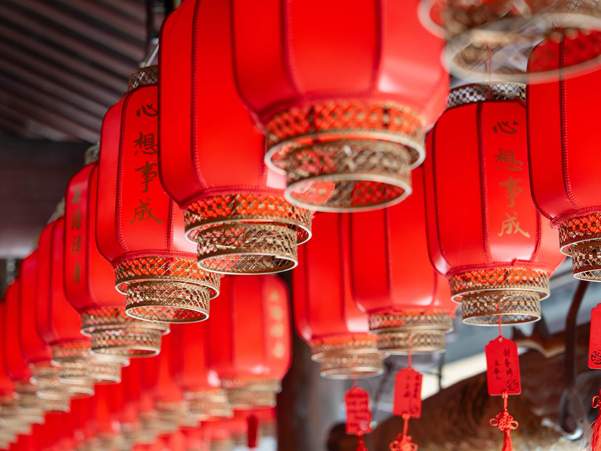 Red lanterns adorned with golden Chinese characters meaning 'May your wishes come true' hanging inside Qita Temple