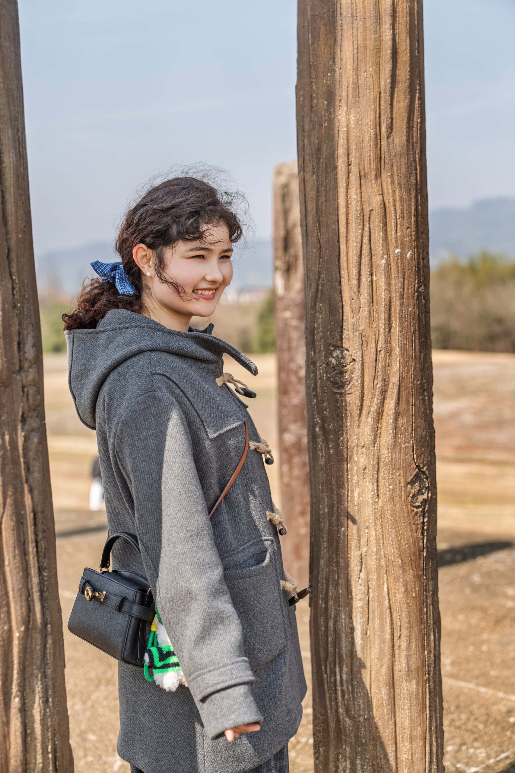A young woman standing among wooden pillars at Mojiaoshan Palace Complex, Liangzhu City China