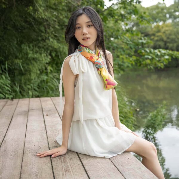 Close-up of a woman in a white outfit adorned with a Wensli Silk Scarf