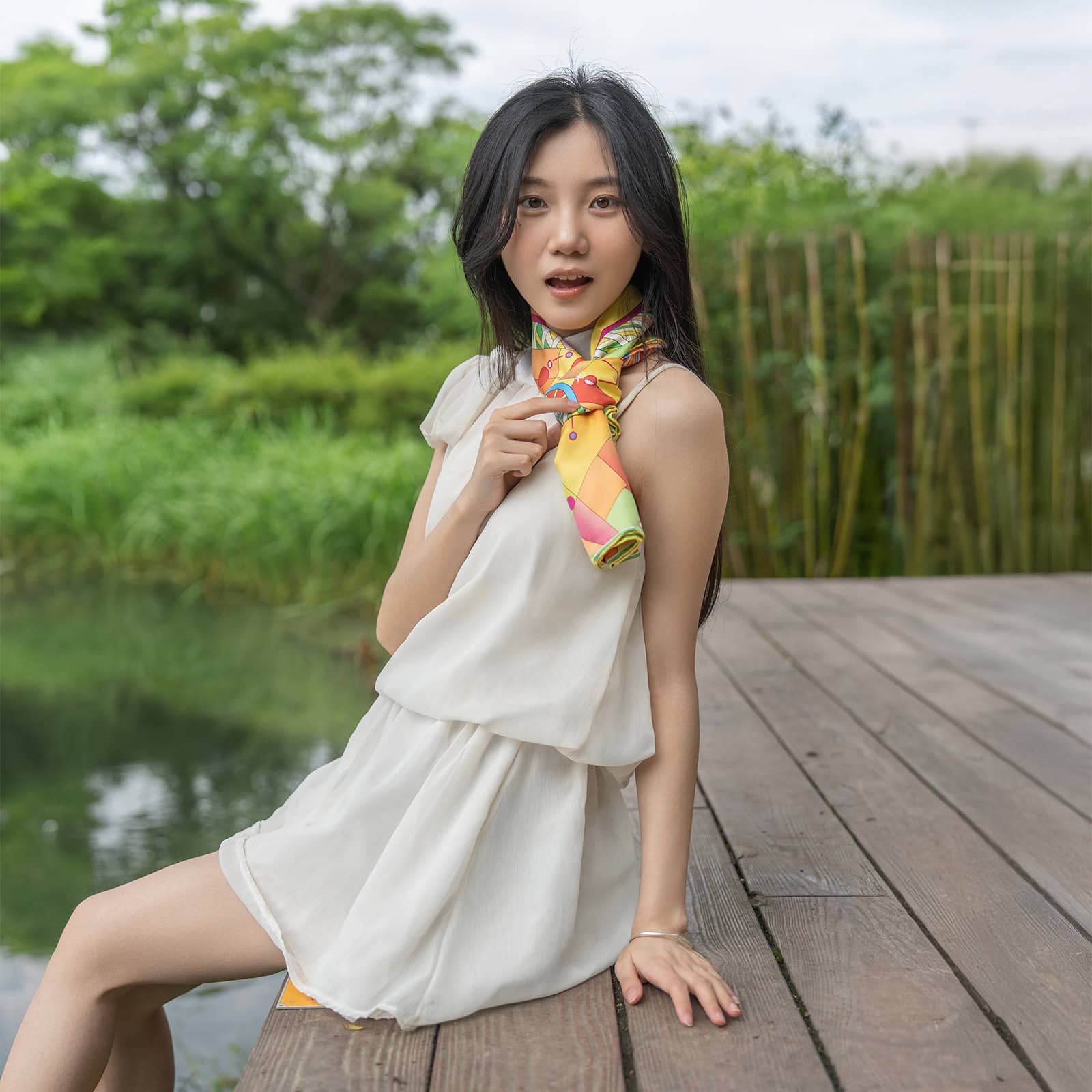 Model poses confidently in a white dress with a Wensli Silk Scarf