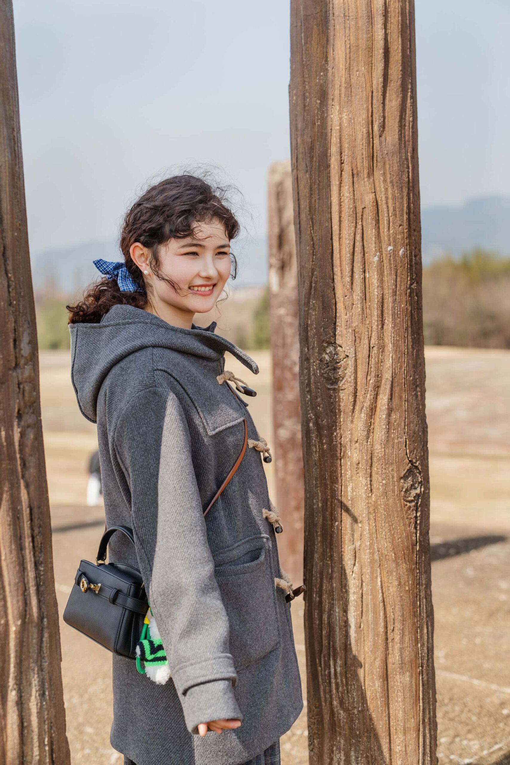 Xinjiang girl smiling by wooden columns at the Archaeological Ruins of Liangzhu City China