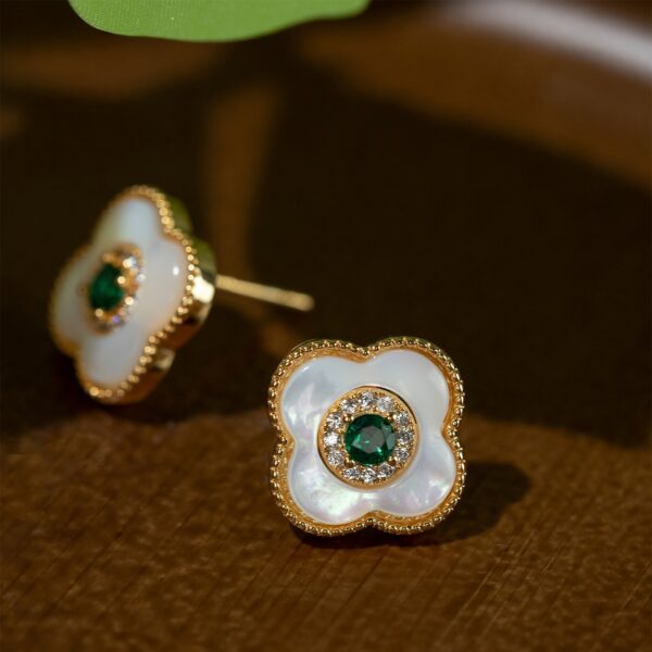 Elegant stud earrings in the shape of a four leaf clover, with a luminous natural shell base and a highlight of green zircon, symbolizing luck and beauty.