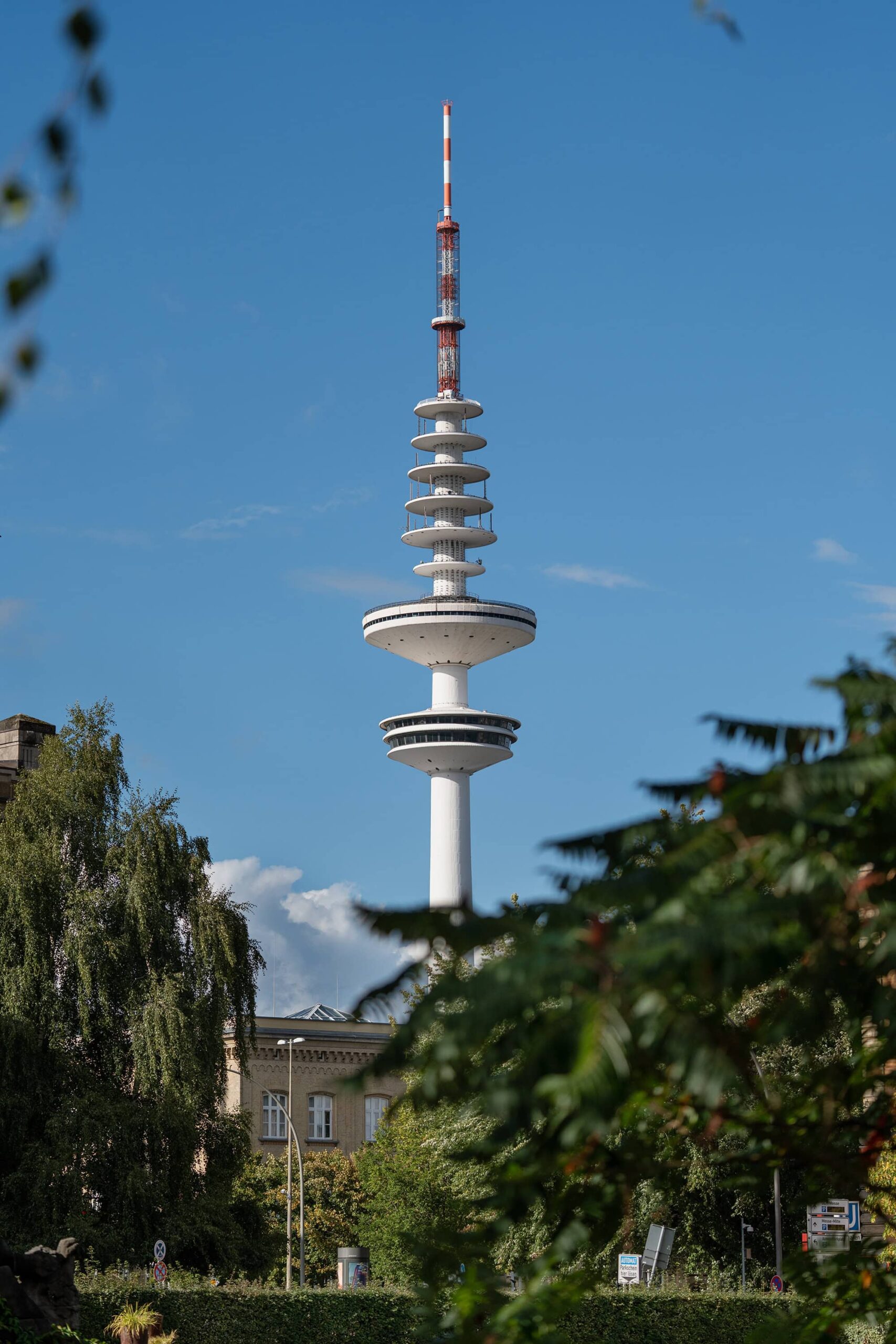 Clear view of the Heinrich Hertz Turm above the trees at Hamburg park Planten un Blomen, blending greenery with the city skyline