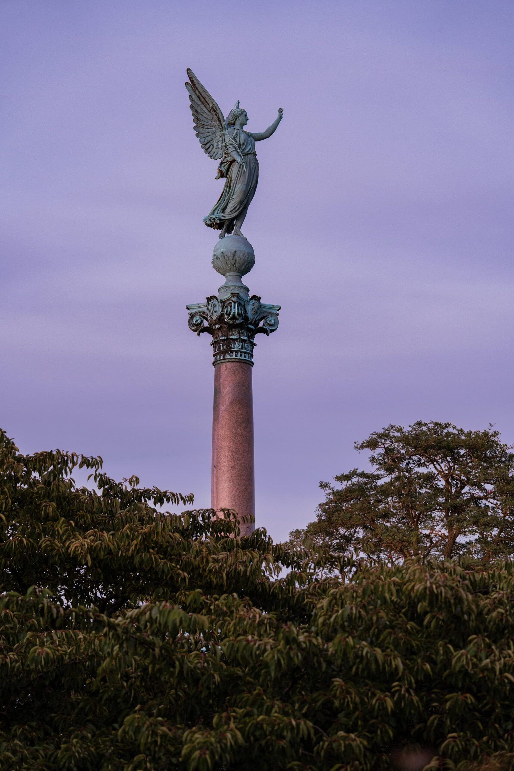 Close-up of the Ivar Huitfeldt Memorial Column in Copenhagen, with the bronze Roman goddess of victory poised above the ornate base