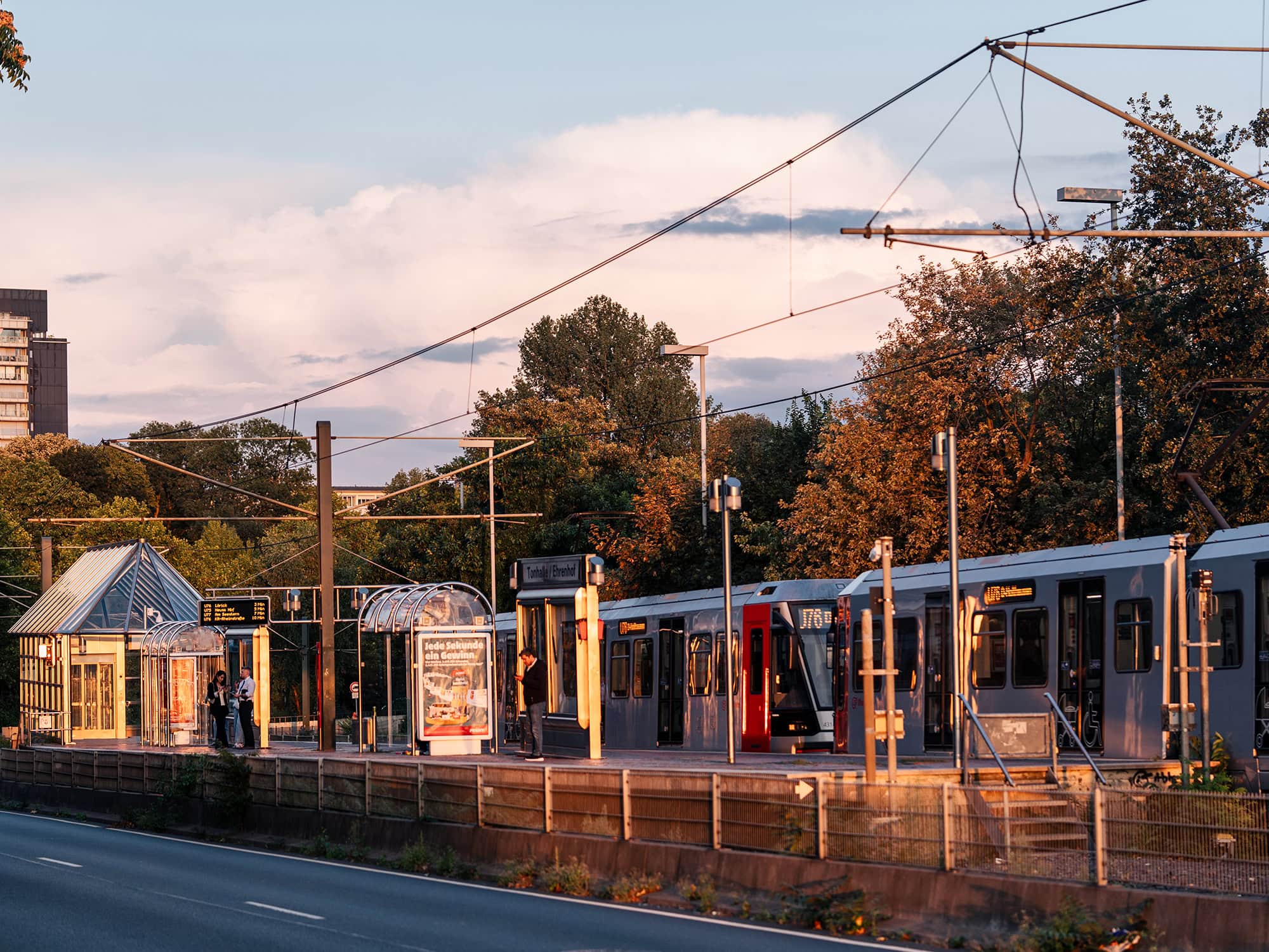 Evening tram stopping by the Tonhalle:Ehrenhof station in Düsseldorf, surrounded by autumn trees and golden light