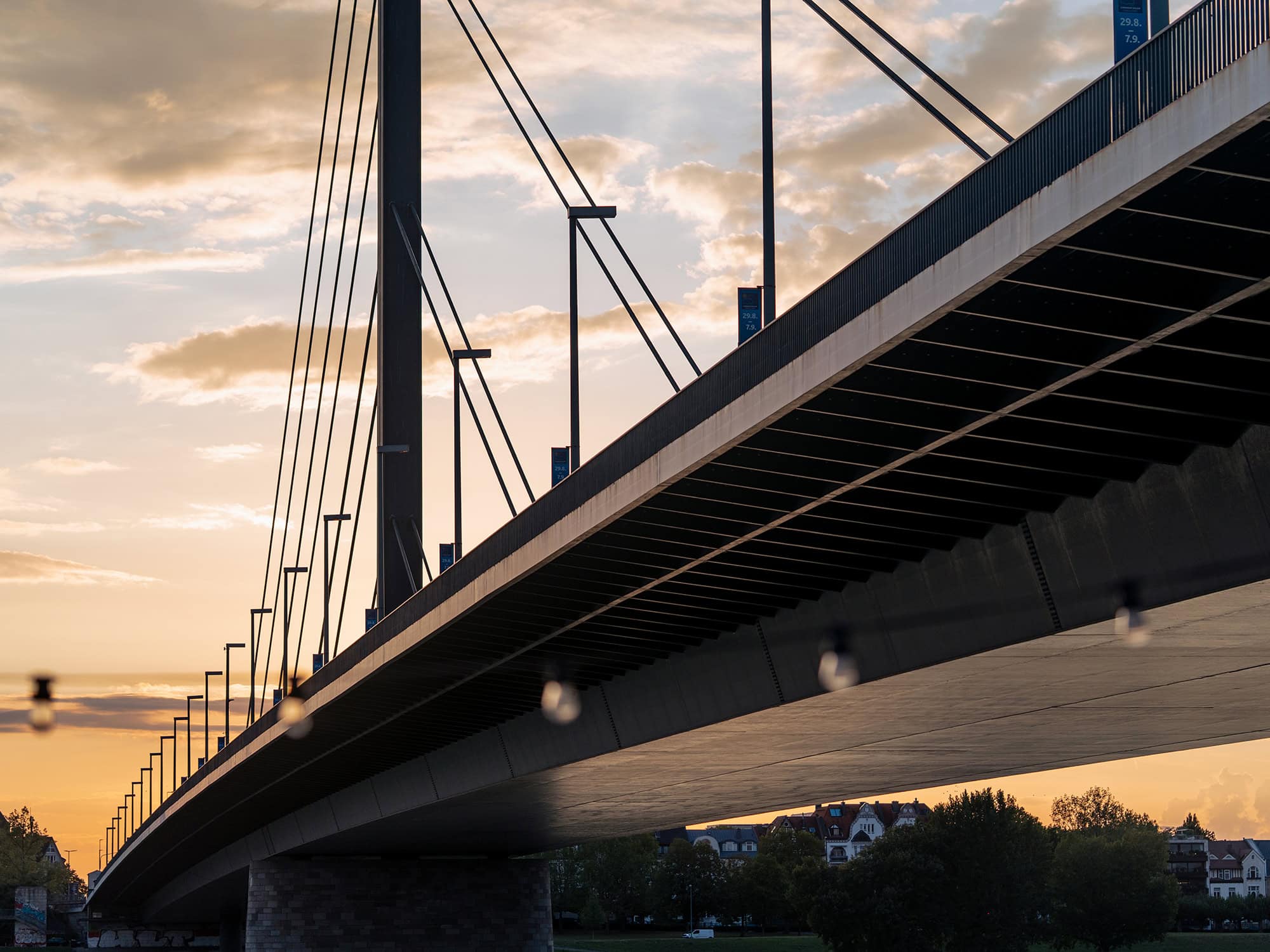 Modern bridge crossing the Rhine near Tonhalle Düsseldorf and Kunstpalast, under a dramatic evening sky