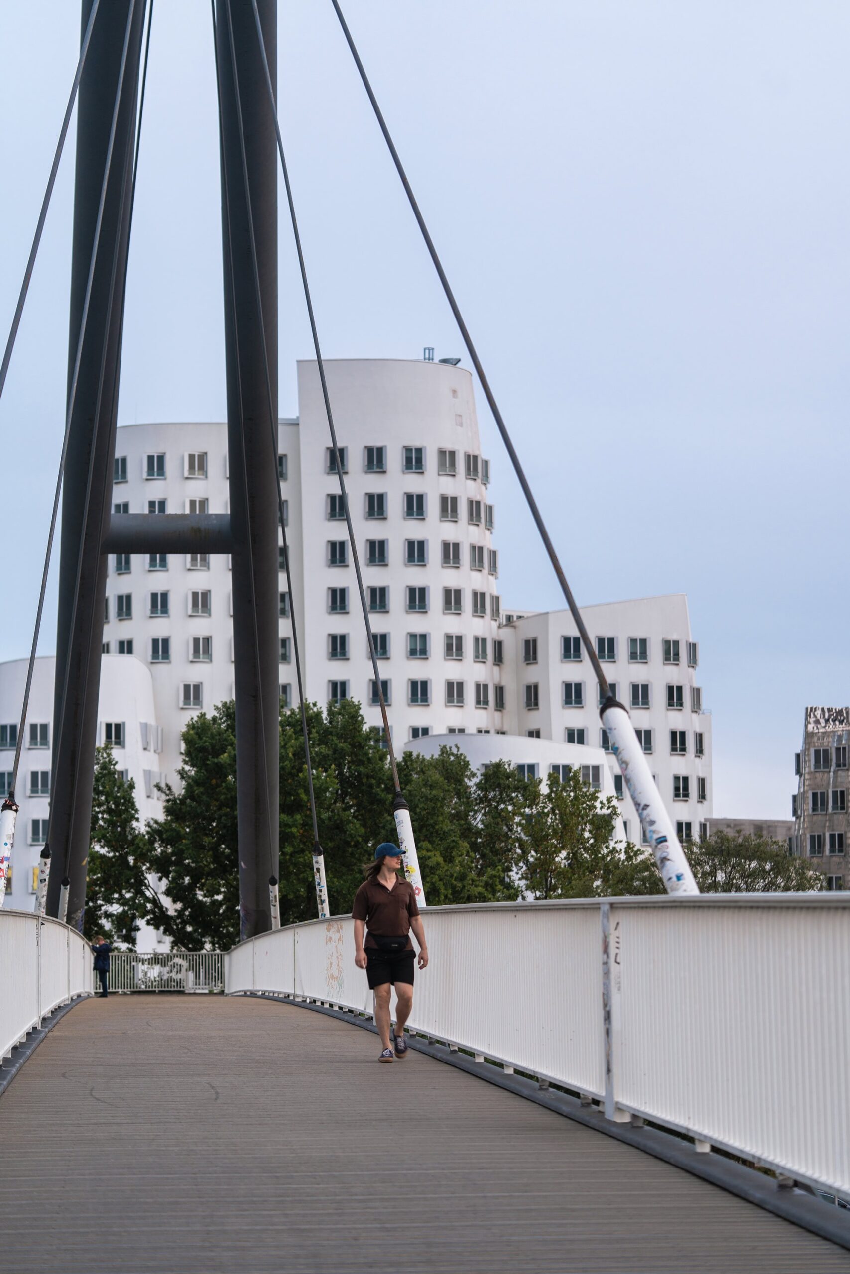 Pedestrian walking away from the white curved buildings of Neuer Zollhof in MedienHafen Düsseldorf