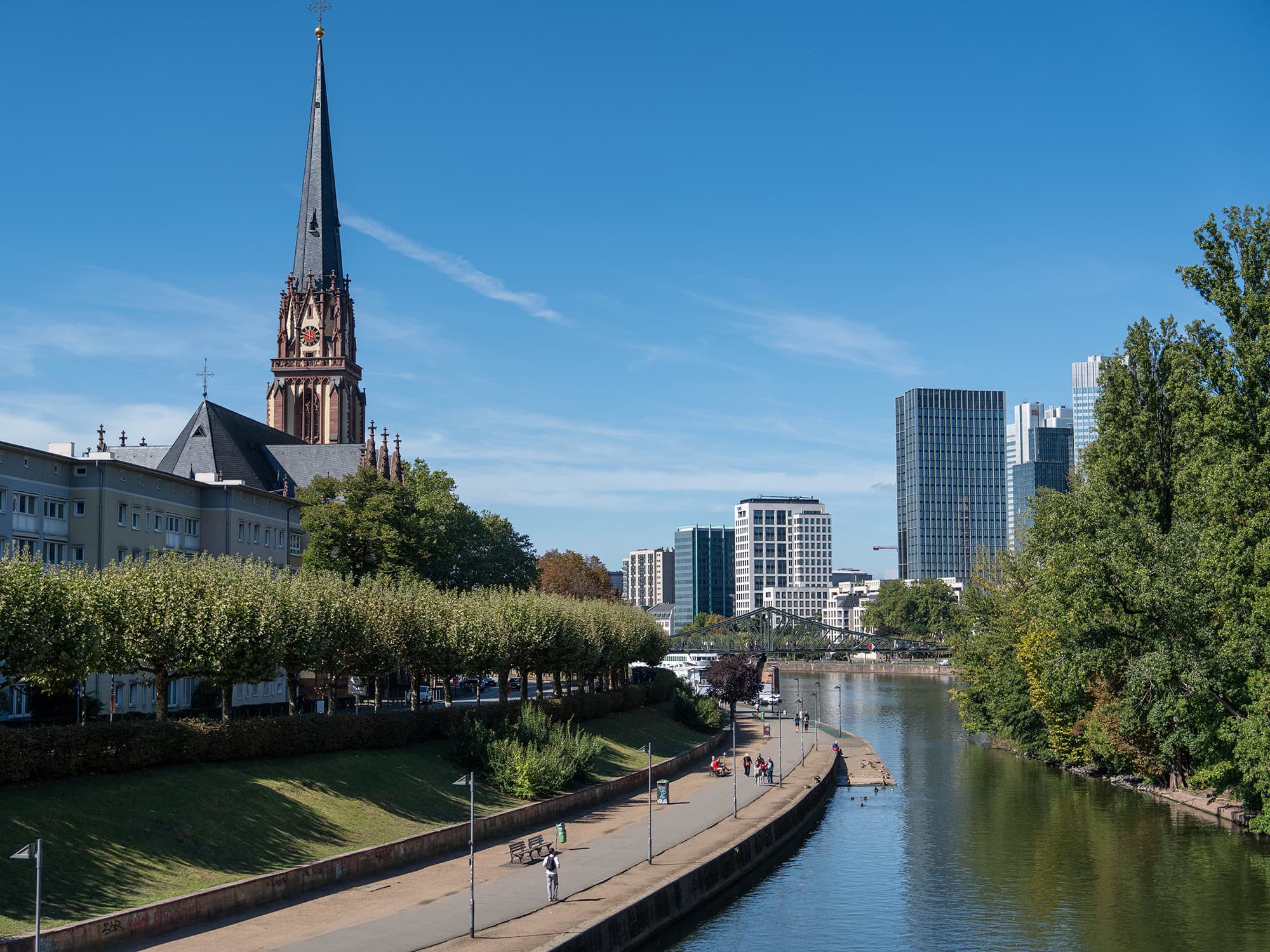 The Gothic spire of Dreikönigskirche and the riverside promenade along the Main