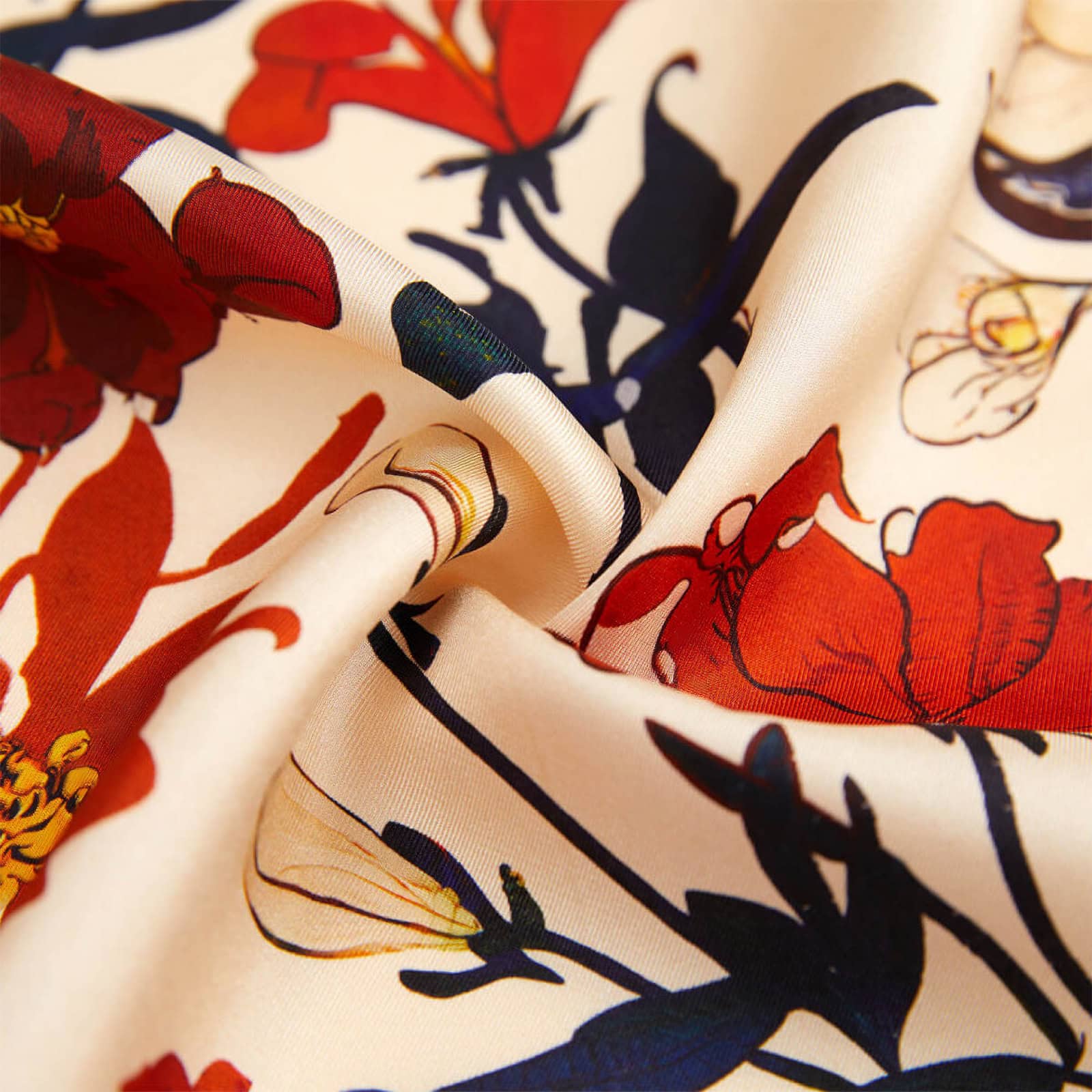 Close-up of the fabric texture of a mulberry silk scarf from China, showing detailed red and dark blue floral prints on twill silk and revealing the scarf’s softness and sheen