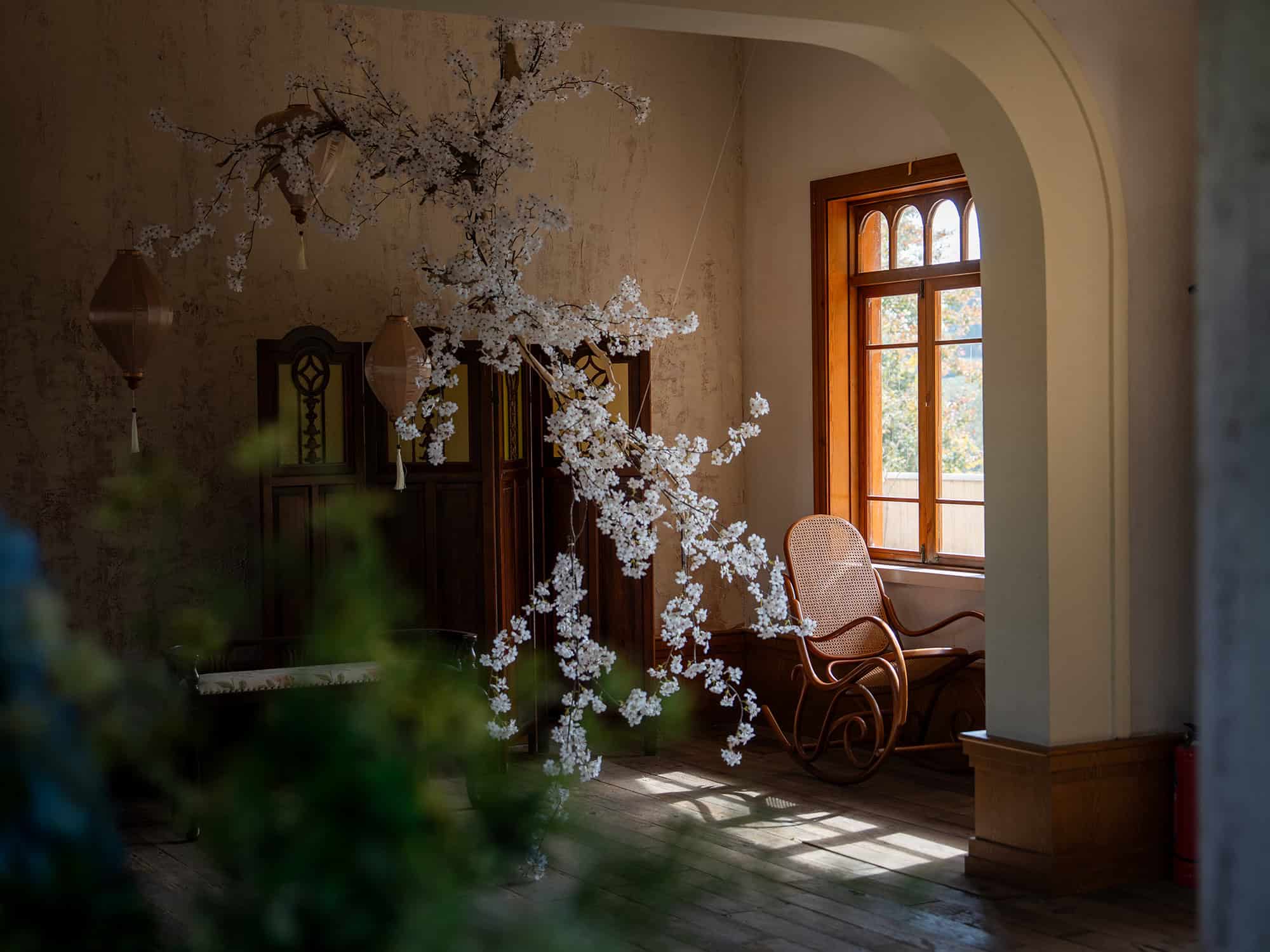 Cozy corner at Yunxi Manor with a vintage wooden rocking chair, soft sunlight through arched windows, and floral decor