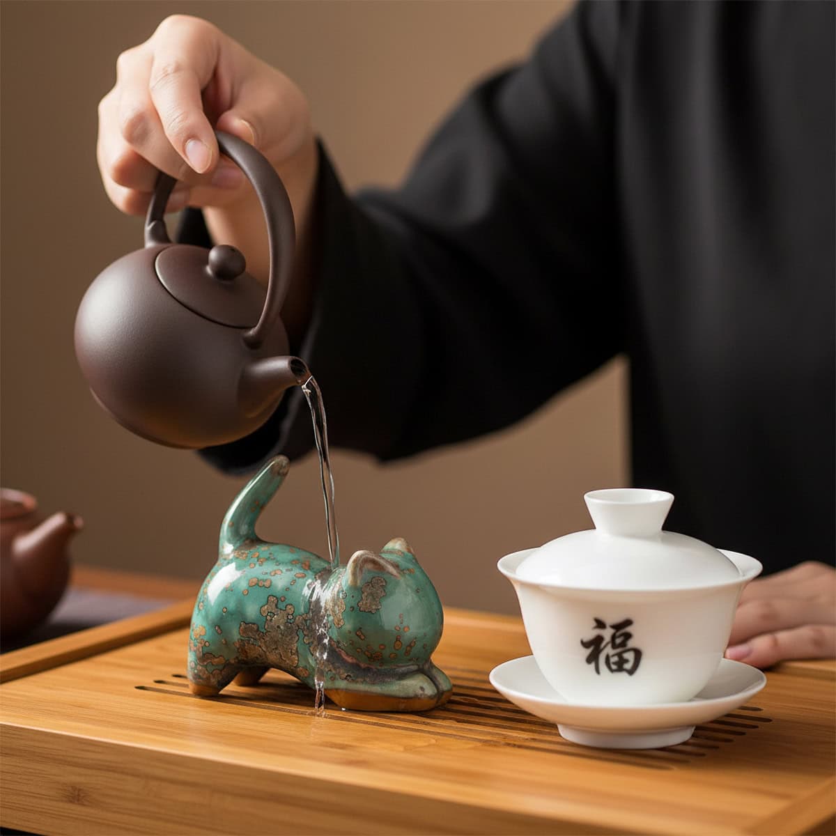 Chinese tea pet cat figurine on tray while water is poured from clay teapot
