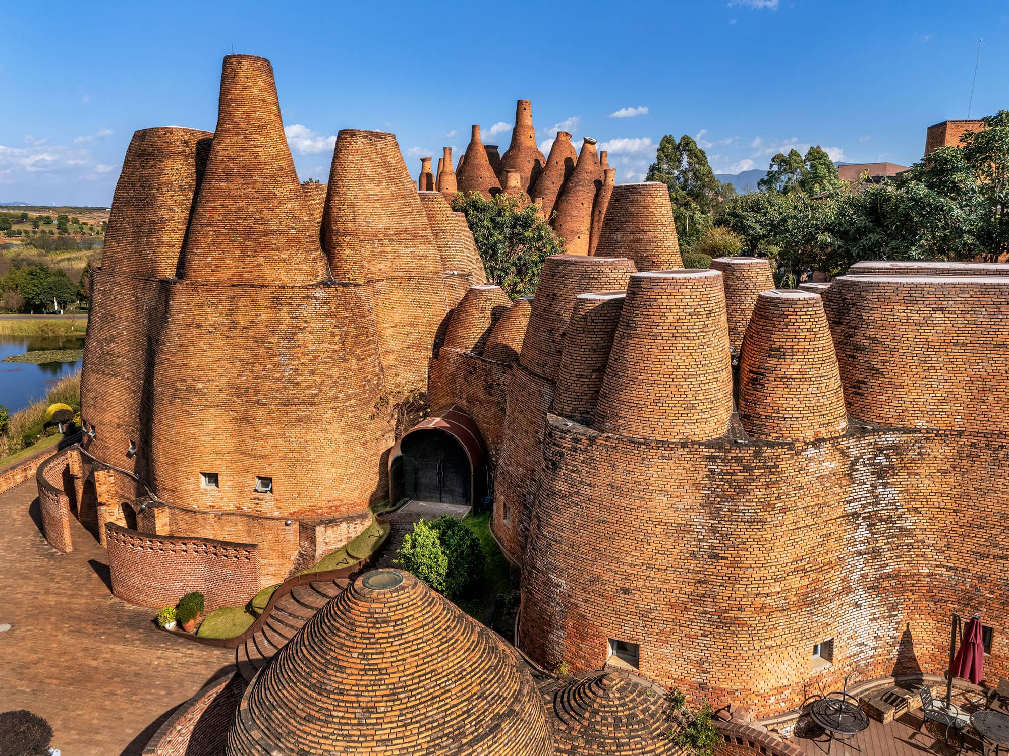 Close aerial view of Mile's Kaleidoscope Art Museum, a postmodern red brick landmark in Dongfengyun Art Town with clustered bottle-like structures