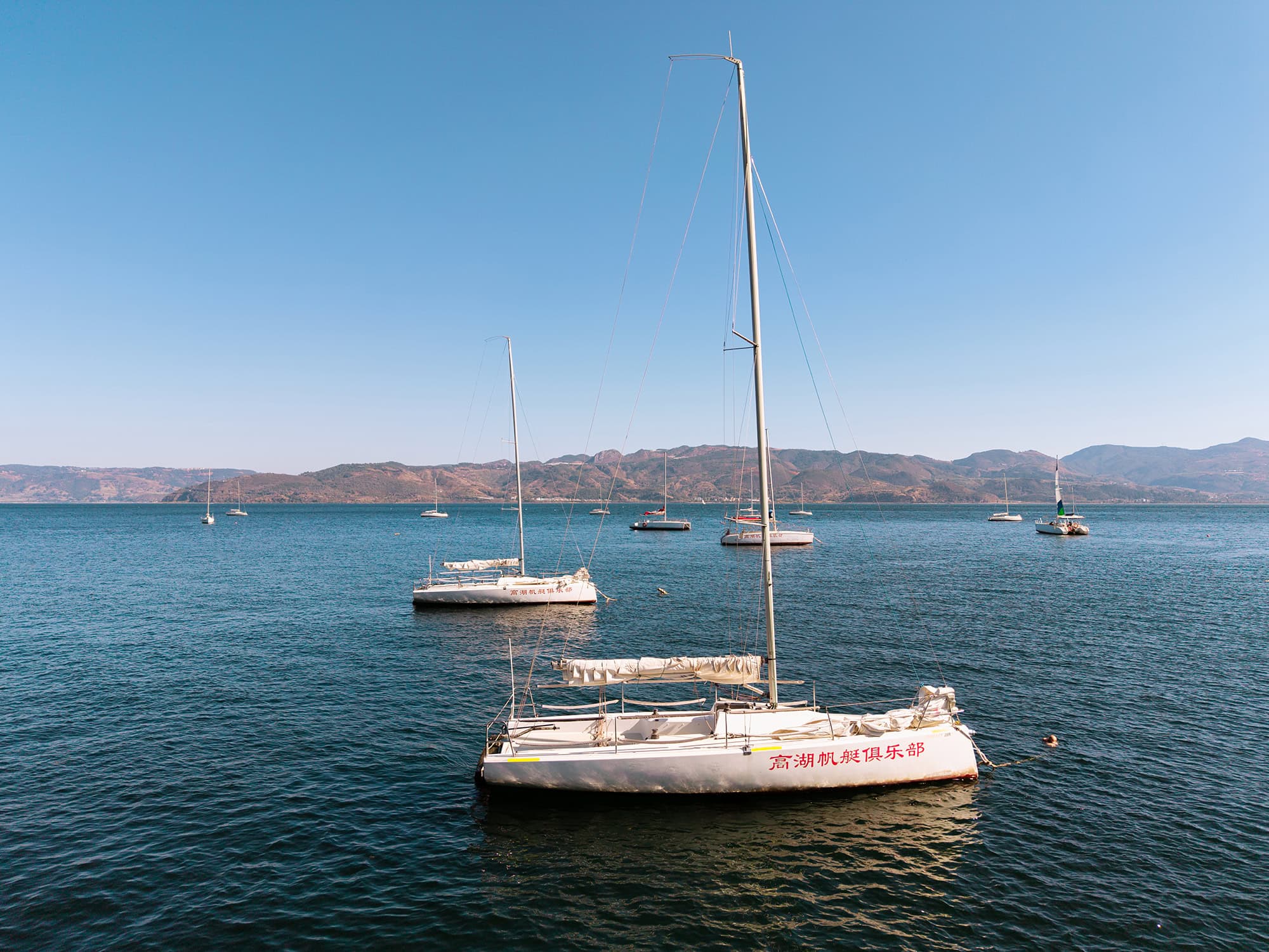 Close-up view of a sailboat on Fuxian Lake at Mingxing Fish Cave, calm water and mountain backdrop