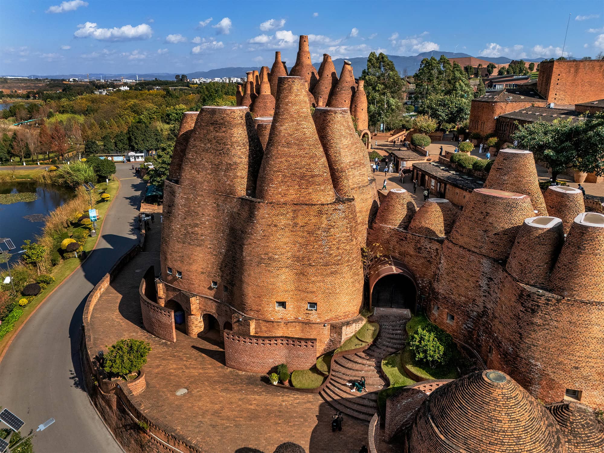 Kaleidoscope Art Museum in Dongfengyun Art Town, Mile, showing the sculptural red brick wine bottle architecture beside roads and greenery