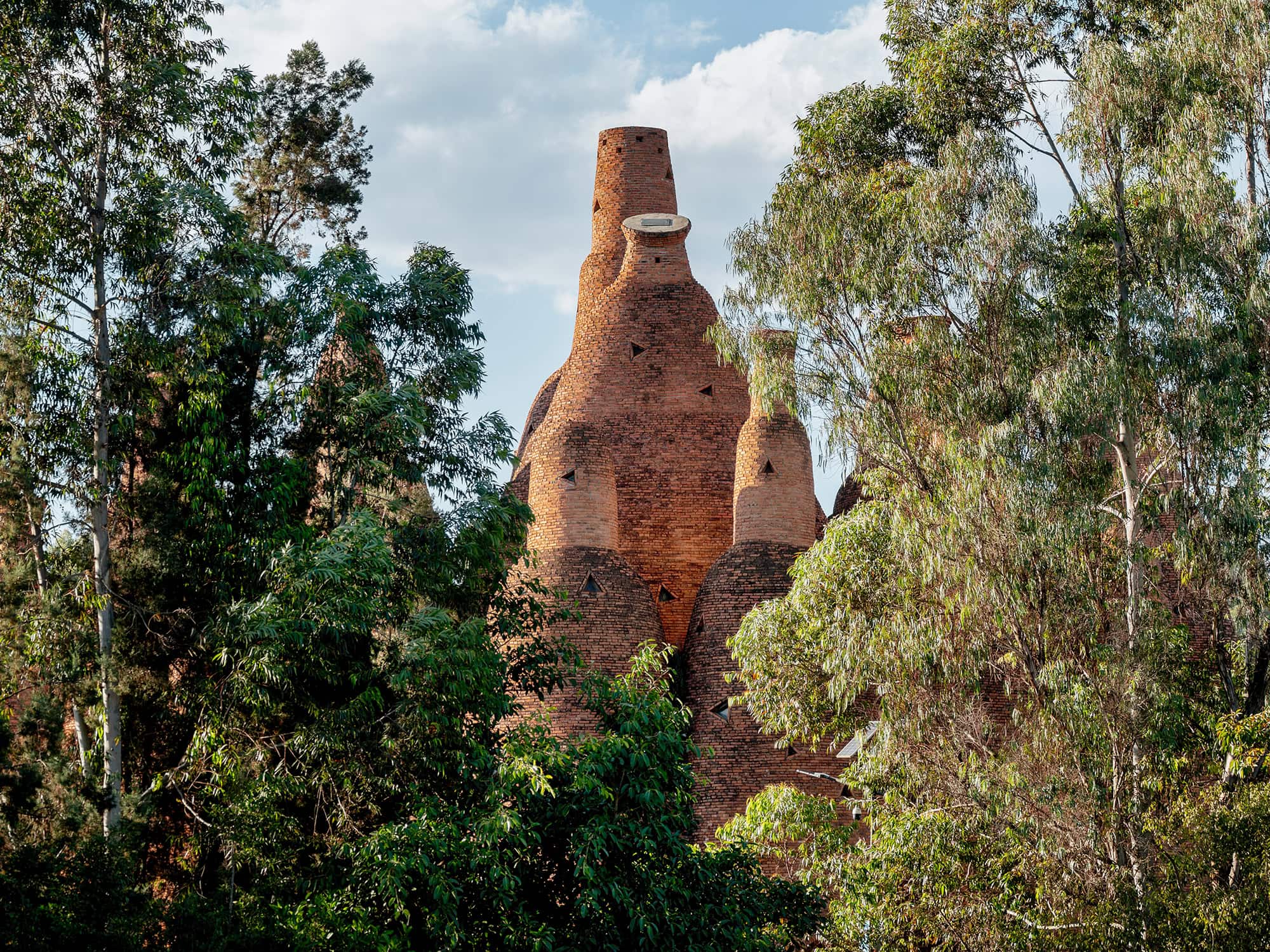 The Kaleidoscope Art Museum’s tall red brick tower rising above trees in Dongfengyun Art Town, Mile