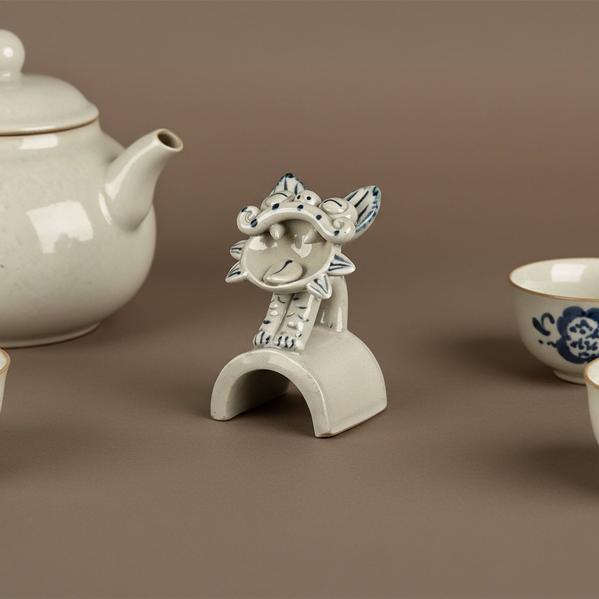 Blue and grey standing Wamao ceramic cat statue decor displayed beside a teapot and cup