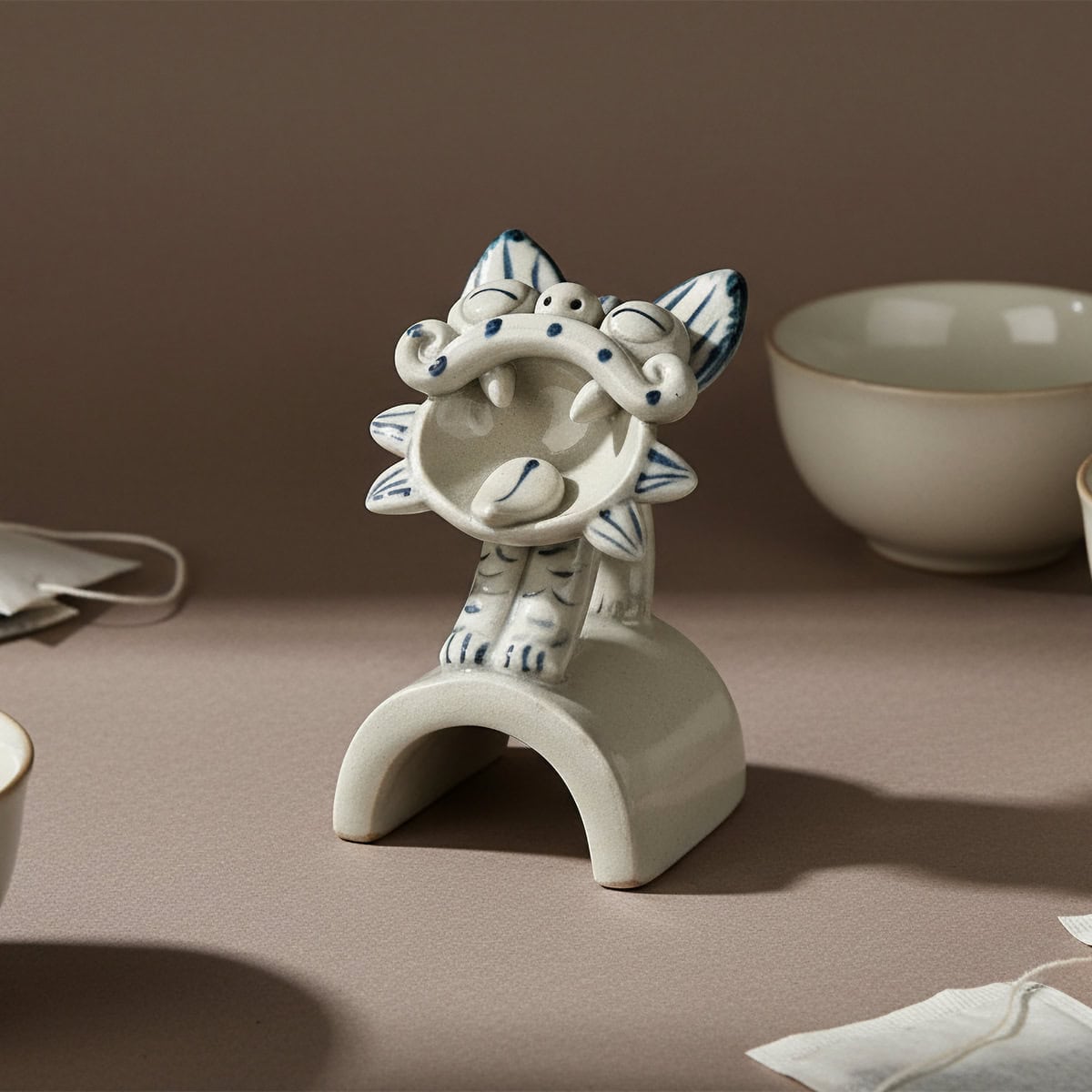 Front angle of a blue and grey Wamao ceramic cat statue decor with open mouth and striped details